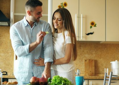 Happy young couple in the kitchen. Handsome man meet and feed his girlfriend early morning at home