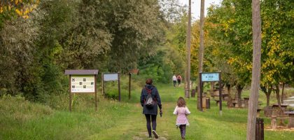 A parent and child walking on a path in a scenic nature reserve in Croatia, surrounded by lush greenery.